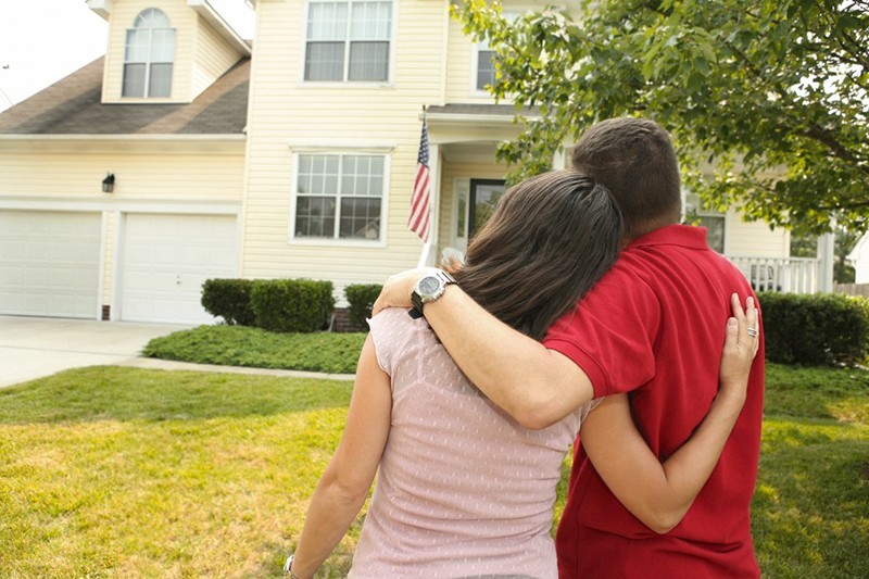 couple standing in front of a house with arm around each other